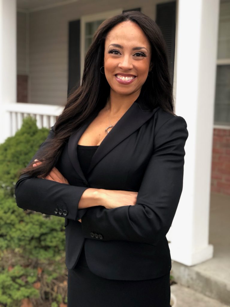 Sade Turner, a young Black woman with long brown hair and brown eyes wearing a black suit