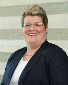 Robin Craig, a middle-aged woman with short blonde hair and blue eyes wearing a navy blazer over a white blouse