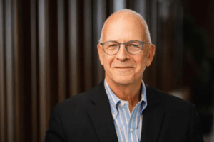 Professor Amos Guiora, a white man with grey hair wearing round-rimmed glasses and a blue-and-white-striped button-up and navy blazer