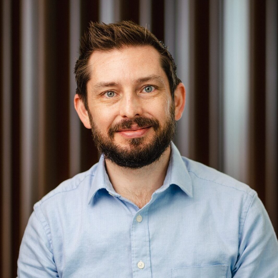 Lance Finch, a middle-aged man with dark hair and beard with blue eyes wearing a blue collared shirt