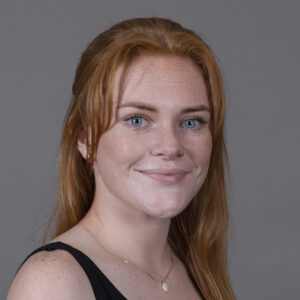 a young woman with ginger hair, freckles and light blue eyes