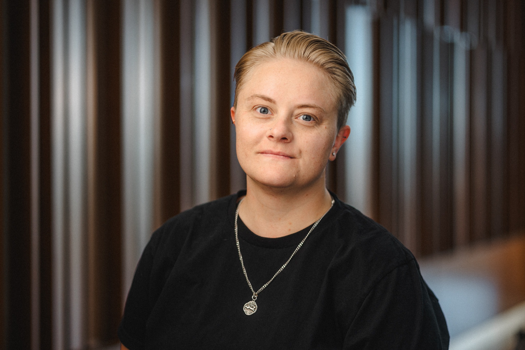 a young woman with short blonde hair combed back wearing a black shirt