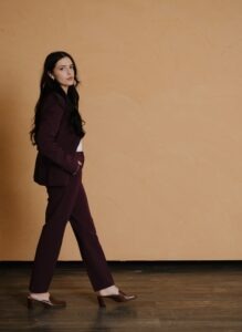 Shyanne Blackburn, a young Navajo woman with long dark-brown hair wearing a dark red pant suit and heels