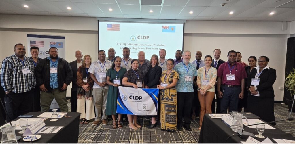 Group of men and women in a conference room in Fiji holding a banner that says "CLDP"