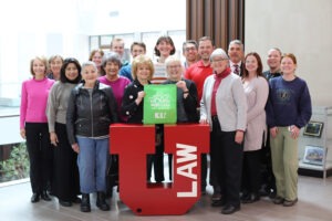 Members of the Public Interest Law Organization (PILO) stand around a red letter "U" to celebrate a gift from 100 Women Who Care