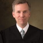 Judge Stephen Nelson, a middle-aged white man with short brown hair graying at the temples wearing a black judge robe